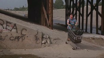 Movie still from “Alligator” (1980), directed by Lewis Teague – A man pushing a shopping cart down a street; Wide shot, High angle