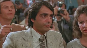 Movie still from “Alligator” (1980), directed by Lewis Teague – A person wearing a suit and a tie; Close Up shot, Over the shoulder angle