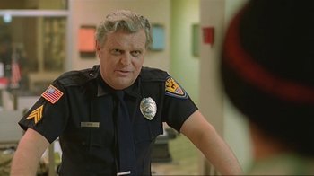 Movie still from “Alligator” (1980), directed by Lewis Teague – A police officer in uniform is standing in a room; Medium shot, Low angle