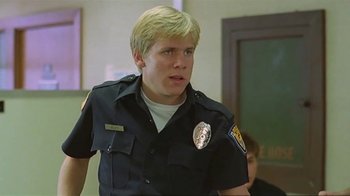Movie still from “Alligator” (1980), directed by Lewis Teague – A police officer in uniform is standing in front of a wall; Close Up shot, Low angle