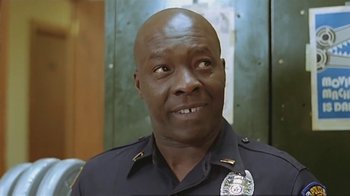 Movie still from “Alligator” (1980), directed by Lewis Teague – A person wearing a police uniform; Close Up shot, Low angle