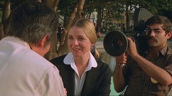 Movie still from “Alligator” (1980), directed by Lewis Teague – A woman is being interviewed by a camera man; Medium shot, Over the shoulder angle