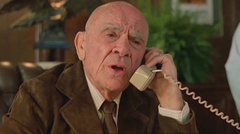 Movie still from “Alligator” (1980), directed by Lewis Teague – An older man talking on a phone while wearing a suit; Close Up shot, Low angle