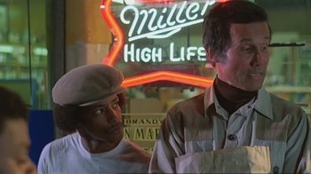 Movie still from “Alligator” (1980), directed by Lewis Teague – Two men standing in front of a miller high life neon sign; Medium shot, Low angle