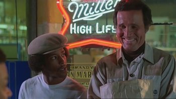 Movie still from “Alligator” (1980), directed by Lewis Teague – Two men standing next to each other in front of a miller high life neon sign; Medium shot, Low angle