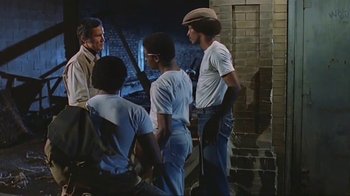 Movie still from “Alligator” (1980), directed by Lewis Teague – A group of men standing next to each other in front of a brick wall; Medium shot, Over the shoulder angle