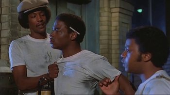 Movie still from “Alligator” (1980), directed by Lewis Teague – A group of young men standing next to each other in a room; Medium shot, Over the shoulder angle