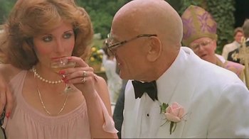 Movie still from “Alligator” (1980), directed by Lewis Teague – An older man in a white tuxedo and a woman in a pink dress; Close Up shot, Low angle