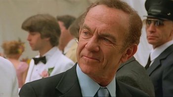 Movie still from “Alligator” (1980), directed by Lewis Teague – An older man wearing a suit and tie in front of a group of people; Close Up shot, Low angle
