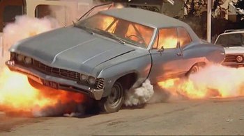 Movie still from “Alligator” (1980), directed by Lewis Teague – An old car on fire with smoke coming out of it; Wide shot, High angle