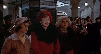 Movie still from “Amarcord” (1973), directed by Federico Fellini – A group of women standing next to each other in front of a building; Medium shot, Low angle