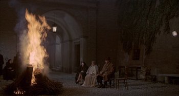 Movie still from “Amarcord” (1973), directed by Federico Fellini – A group of people sitting in front of a bonfire; Wide shot, High angle