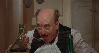 Movie still from “Amarcord” (1973), directed by Federico Fellini – An old man with a mustache and a beard is eating a fork; Close Up shot, High angle