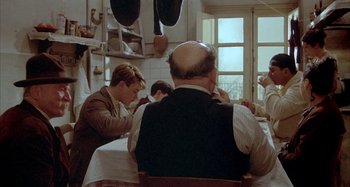 Movie still from “Amarcord” (1973), directed by Federico Fellini – A group of people sitting at a table in a room; Medium shot, Over the shoulder angle