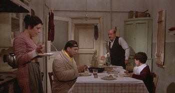 Movie still from “Amarcord” (1973), directed by Federico Fellini – A group of people sitting at a table eating food; Wide shot, High angle