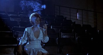 Movie still from “Amarcord” (1973), directed by Federico Fellini – A woman smoking a cigarette while sitting on a chair; Wide shot, Low angle