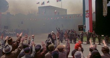 Movie still from “Amarcord” (1973), directed by Federico Fellini – A group of people standing in front of a building; Wide shot, High angle