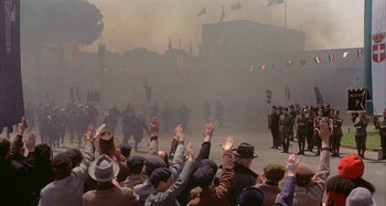 Movie still from “Amarcord” (1973), directed by Federico Fellini – A group of people standing in front of a crowd; Wide shot, High angle