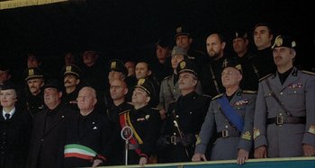 Movie still from “Amarcord” (1973), directed by Federico Fellini – A group of men in military uniforms standing next to each other; Wide shot, Low angle