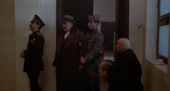 Movie still from “Amarcord” (1973), directed by Federico Fellini – A group of men standing next to each other in a room; Wide shot, High angle