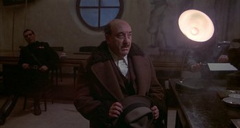 Movie still from “Amarcord” (1973), directed by Federico Fellini – An older man wearing a brown coat and a hat; Medium shot, Low angle