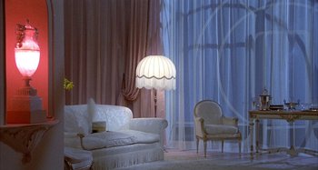 Movie still from “Amarcord” (1973), directed by Federico Fellini – A living room filled with furniture next to a large window; Wide shot, High angle