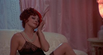 Movie still from “Amarcord” (1973), directed by Federico Fellini – A woman sitting on a couch wearing a red hat; Close Up shot, High angle