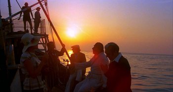 Movie still from “Amarcord” (1973), directed by Federico Fellini – A group of people sitting on top of a sail boat; Wide shot, Low angle