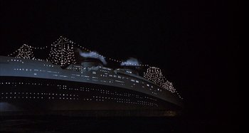 Movie still from “Amarcord” (1973), directed by Federico Fellini – A cruise ship lit up at night in the dark; Extreme Wide shot, Low angle