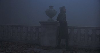 Movie still from “Amarcord” (1973), directed by Federico Fellini – A person walking in the fog near a statue; Wide shot, Over the shoulder angle