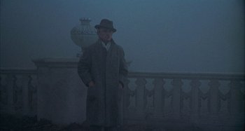 Movie still from “Amarcord” (1973), directed by Federico Fellini – A man in a hat and coat standing in the fog; Wide shot, Low angle