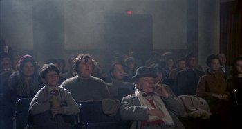 Movie still from “Amarcord” (1973), directed by Federico Fellini – A group of people sitting in a room; Medium shot, Low angle