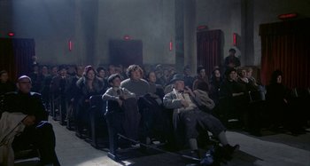 Movie still from “Amarcord” (1973), directed by Federico Fellini – A group of people sitting in a room watching a movie; Wide shot, High angle
