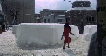 Movie still from “Amarcord” (1973), directed by Federico Fellini – A woman in a red dress walking in the snow; Extreme Wide shot, High angle