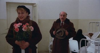 Movie still from “Amarcord” (1973), directed by Federico Fellini – An older man holding a hat in front of a woman; Medium shot, Over the shoulder angle