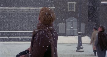 Movie still from “Amarcord” (1973), directed by Federico Fellini – A woman is standing in the snow looking at a street lamp; Medium shot, Over the shoulder angle