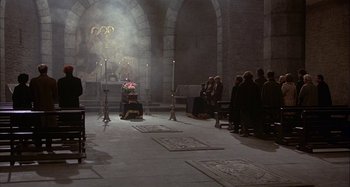 Movie still from “Amarcord” (1973), directed by Federico Fellini – A group of people standing in a room with candles; Wide shot, High angle