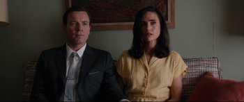 Movie still from “American Pastoral” (2016), directed by Ewan McGregor – A man and a woman sitting next to each other; Medium shot, Low angle