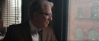 Movie still from “American Pastoral” (2016), directed by Ewan McGregor – An older man wearing a suit and bow tie looking out of a window; Close Up shot, Over the shoulder angle