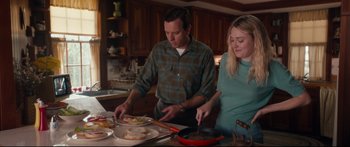 Movie still from “American Pastoral” (2016), directed by Ewan McGregor – A man and a woman preparing food in a kitchen; Medium shot, High angle