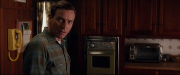 Movie still from “American Pastoral” (2016), directed by Ewan McGregor – A man standing in front of an oven in a kitchen; Medium shot, Over the shoulder angle