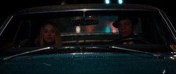Movie still from “American Pastoral” (2016), directed by Ewan McGregor – A man and a woman sitting in the back seat of a car; Medium shot, Low angle