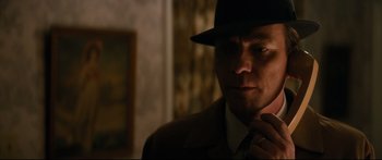 Movie still from “American Pastoral” (2016), directed by Ewan McGregor – A man wearing a hat and a suit and tie; Close Up shot, Over the shoulder angle