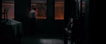 Movie still from “American Pastoral” (2016), directed by Ewan McGregor – A man standing in front of a large window; Wide shot, High angle