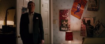 Movie still from “American Pastoral” (2016), directed by Ewan McGregor – A man in a suit standing in front of a poster; Medium shot, Low angle