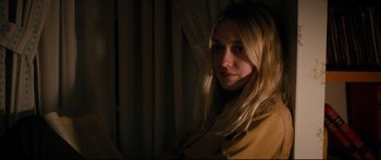Movie still from “American Pastoral” (2016), directed by Ewan McGregor – A woman with long blonde hair looking at the camera; Close Up shot, Over the shoulder angle