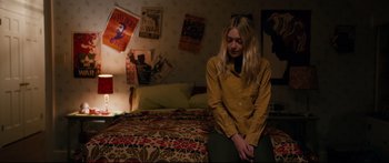 Movie still from “American Pastoral” (2016), directed by Ewan McGregor – A woman sitting on a bed in front of a bunch of posters on the wall; Medium shot, High angle