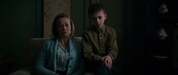 Movie still from “American Pastoral” (2016), directed by Ewan McGregor – A woman sitting next to a young boy in a room; Medium shot, Over the shoulder angle
