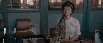 Movie still from “American Pastoral” (2016), directed by Ewan McGregor – A woman sitting at a table with a book in front of her; Medium shot, Over the shoulder angle