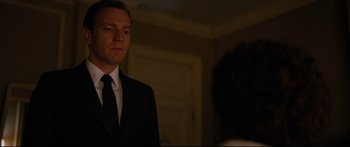 Movie still from “American Pastoral” (2016), directed by Ewan McGregor – A man wearing a suit and tie standing in front of a mirror; Medium shot, Low angle